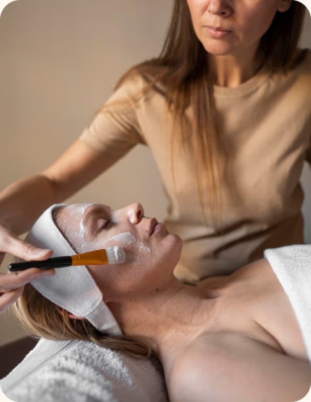Esthetician applying a face mask to a client